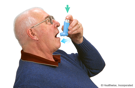 A man pressing on the inhaler and breathing in