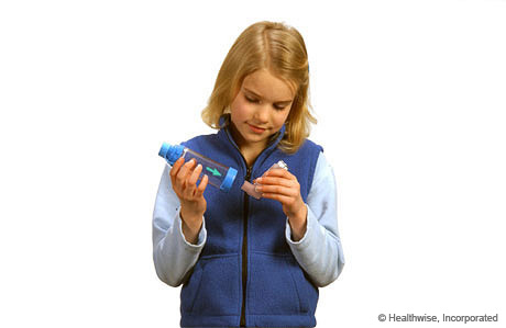 A child putting the inhaler mouthpiece into the spacer