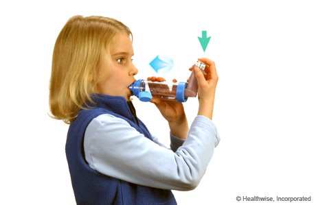 A child pressing down on the inhaler and breathing in